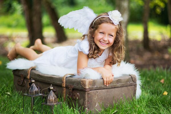 Fille joyeuse sur une valise avec des ailes