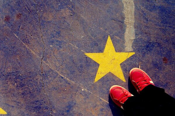 A yellow star is drawn, and a man in red sneakers is standing next to it