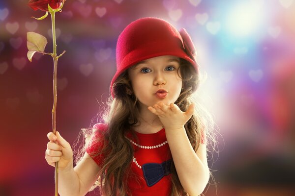 Enfant dans des vêtements rouges et avec une rose dans les mains