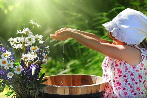 Ein Mädchen gießt Wasser in ein Blumenbecken