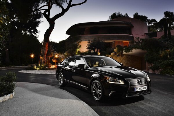 Berline noire Lexus LS soirée à côté de la maison