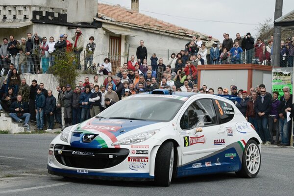 Cute white and blue peugeot surrounded by spectators