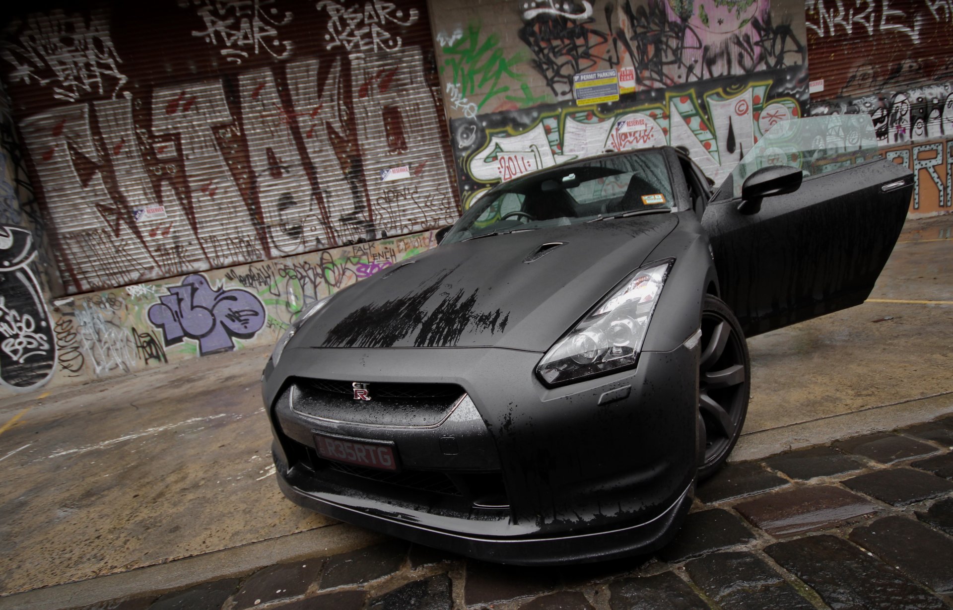 nissan gt-r noir mouillé avant graffiti