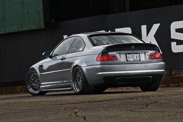 BMW M3 rear view on the photo of the wall with the inscription