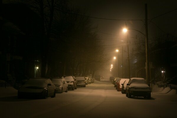 Schneebedeckte Nacht zwischen Straßen und Autos