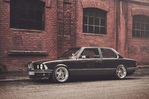 Un BMW E21 coupé negro contra un antiguo edificio de ladrillo