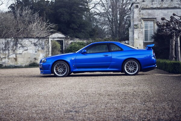 Blauer Nissan Skyline in der Nähe des alten Hauses