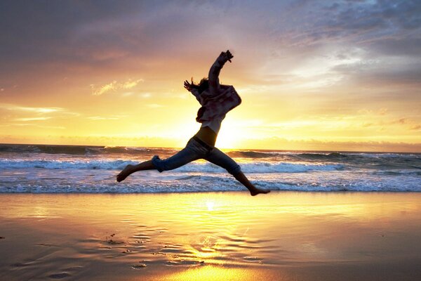 Photo de sauter sur la plage au coucher du soleil