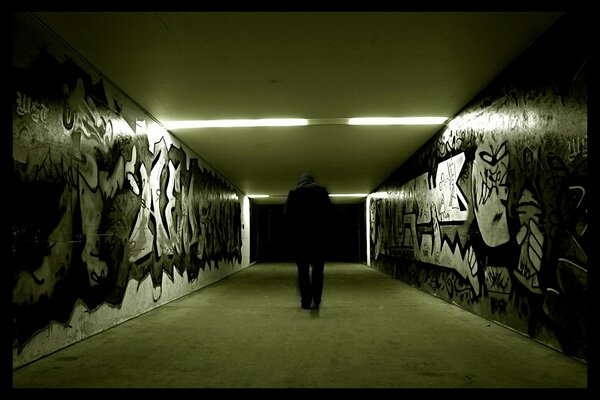 Człowiek idący korytarzem w grafiti