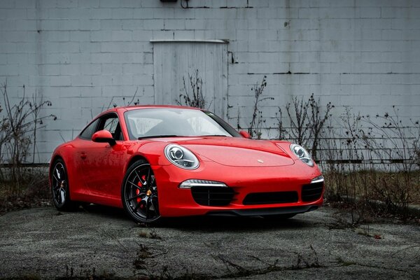 Auto Porsche di colore rosso su sfondo muro