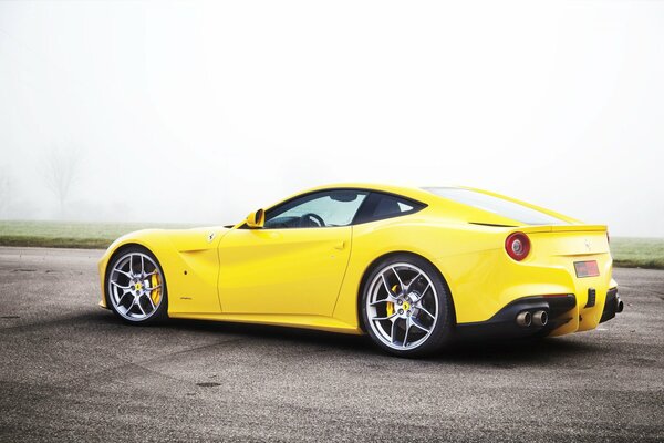 Yellow sports car. Side view. Against the background of fog