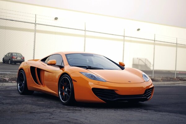 Coche de color naranja cerca de la valla