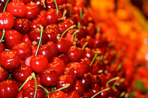 Glossy cherry berry on an orange background from other berries