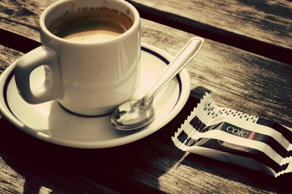 Чашка кофе в блюдце и конфетой