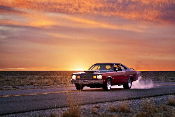 Voiture sur la route sur fond de coucher de soleil