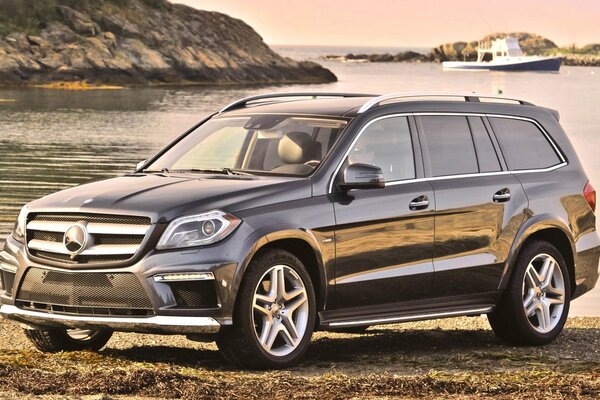 Mercedes-benz jeep on the shore against the background of a boat