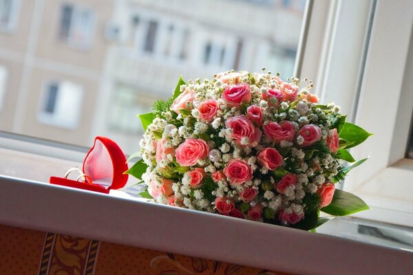 Ramo de rosas y anillos de boda en una Caja en el alféizar de la ventana