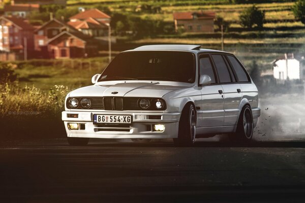 BMW E30 blanco en el fondo de los suburbios