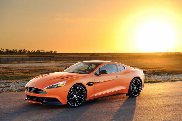 Orange Aston Martin im Hintergrund des Sonnenuntergangs