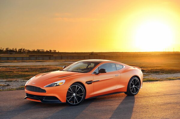 Оранжевый aston martin на фоне заката