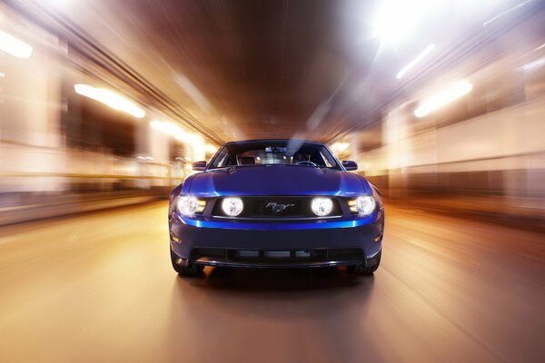 Une Ford Mustang bleue roule à grande vitesse