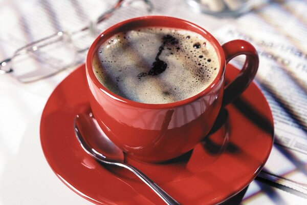 Tasse de café dans une tasse rouge debout sur le journal du matin