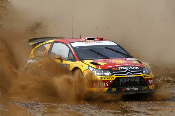 The car participates in the rally and creates splashes on the turn