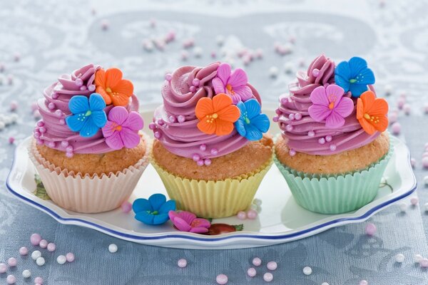 Die bunten Muffins sind mit Blumen und mehrfarbiger Creme verziert