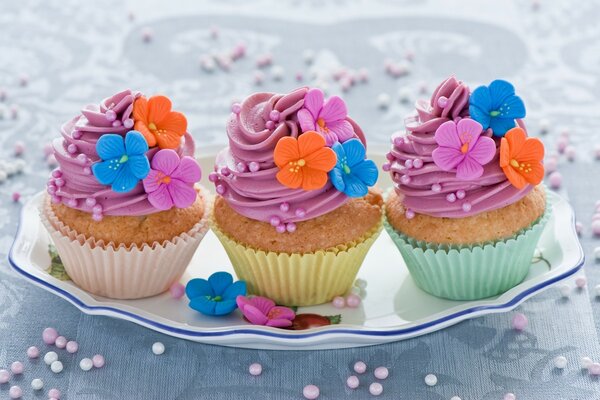 Cupcakes colorés décorés avec des fleurs et de la crème multicolore