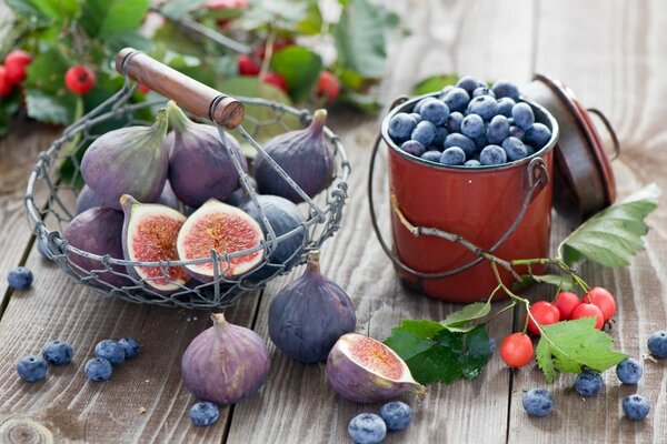 Korb mit Feigen und einem Eimer Blaubeeren