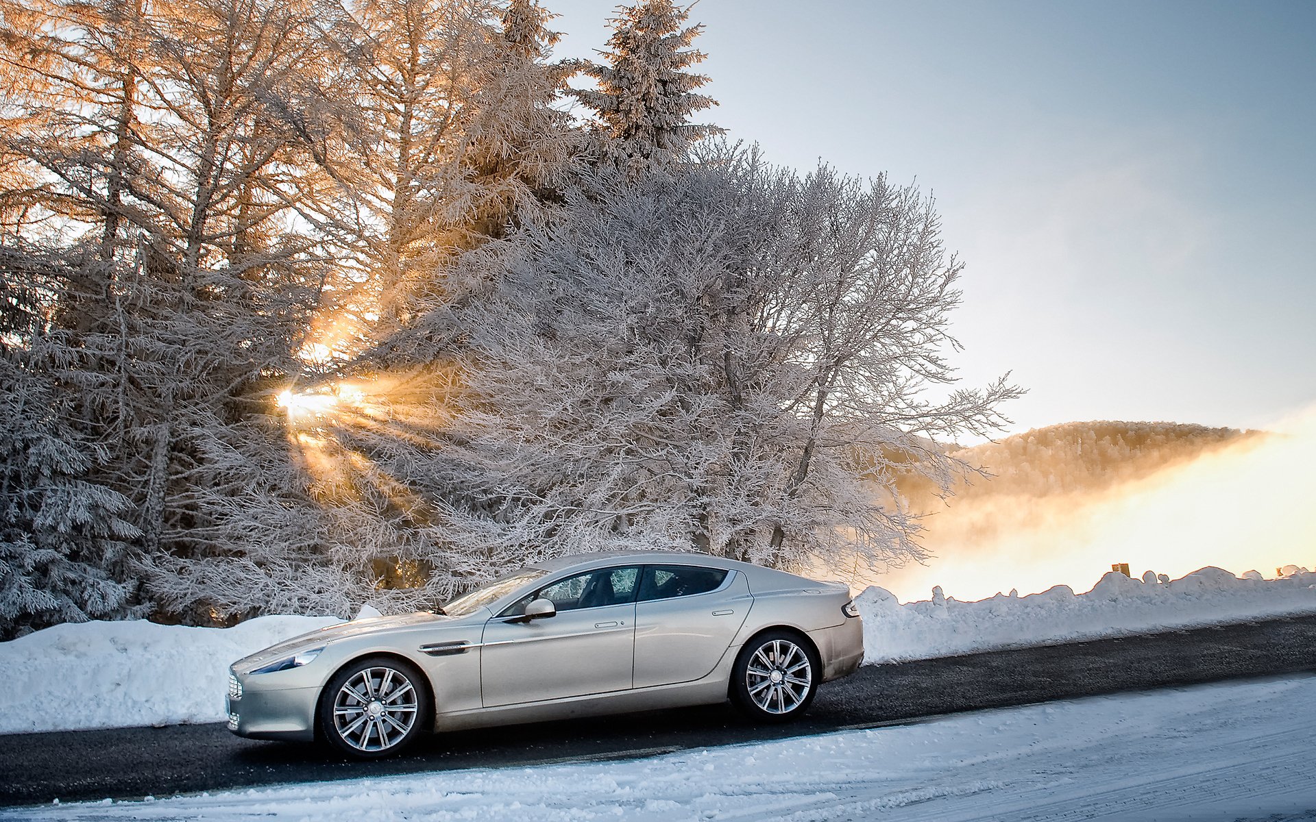 aston martin rapide aston martin rapid sedan widok z boku zima śnieg drzewa niebo słońce