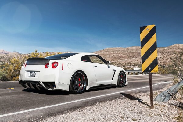 Blanco Nissan GTR en la carretera en las montañas