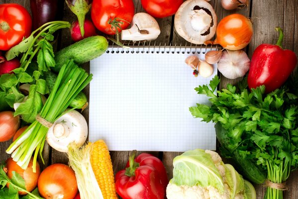 Notebook on the background of vegetables and greenery