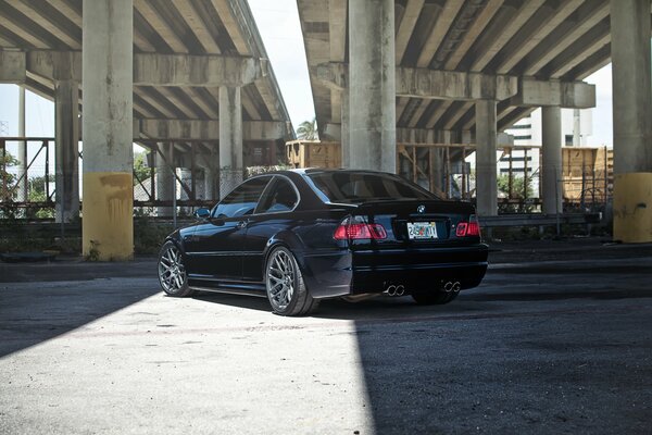 Dark blue BMW on the background of concrete pillars