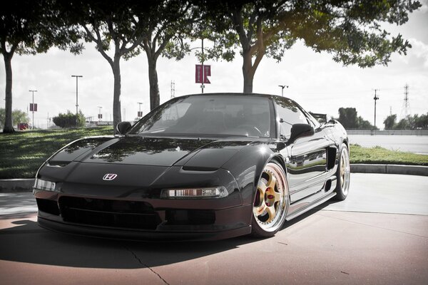 Black Honda Acura with yellow alloy wheels standing in the parking lot