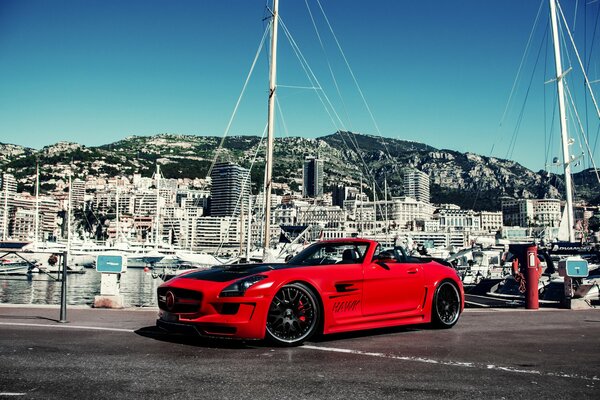 Mercedes rouge sur fond de bâtiments et yachts