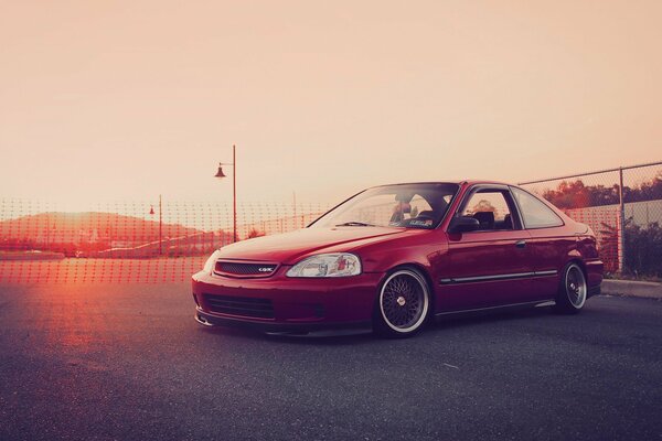 Un Honda Civic rojo en medio de la puesta de sol