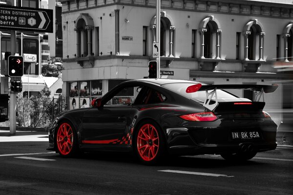 Porsche noire avec Jantes rouges au carrefour de la ville