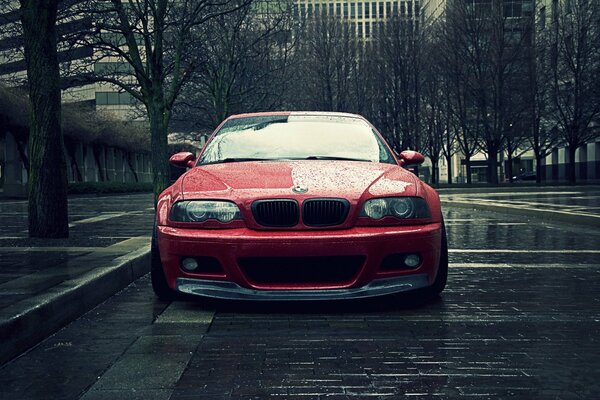 Red BMW e46 in a rainy city