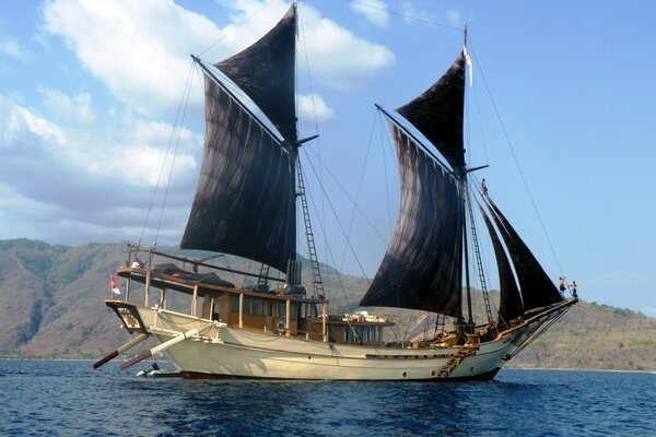 Navire avec des voiles noires dans la mer bleue