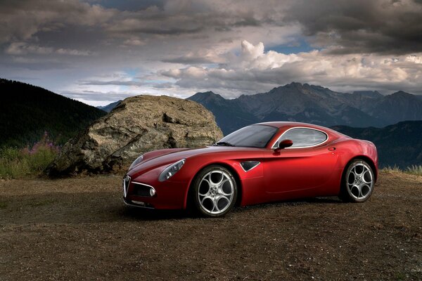 Alfa Romeo rossa sullo sfondo di un paesaggio montano