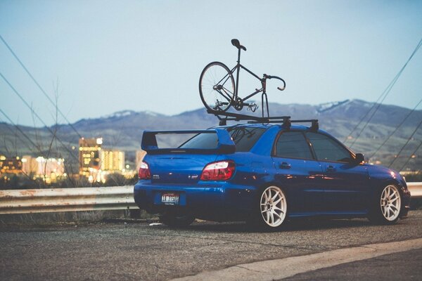 Subaru impreza wrx is on the road with a bike on the roof