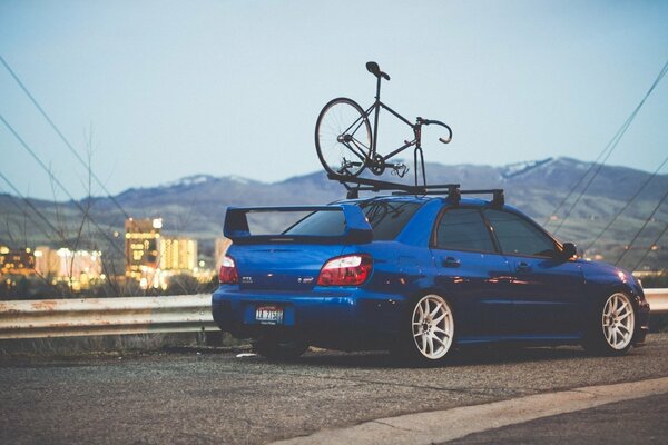 Subaru impreza wrx si trova sulla strada con una bici sul tetto