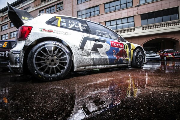 Rally foltsvagen Polo después de correr en el barro, reflejo en un charco