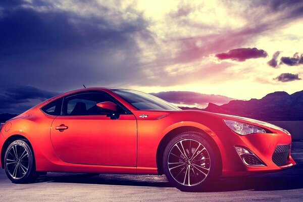 Against the background of a stormy sky - a red Subaru sports car