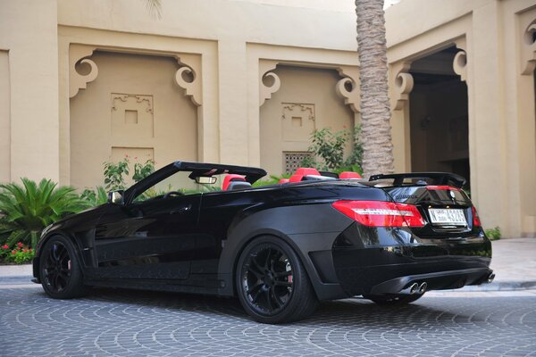 Black luxury car at the house with palm trees