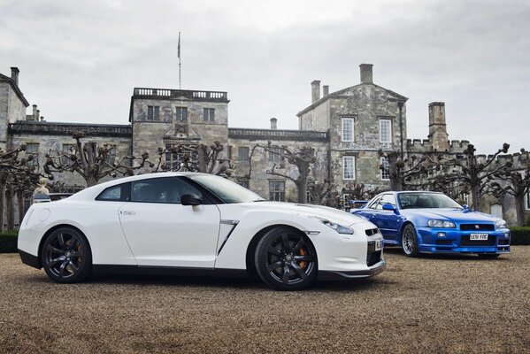 White and blue Nissan on the background of a beautiful house with trees