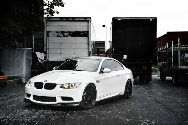 BMW blanco junto a camiones