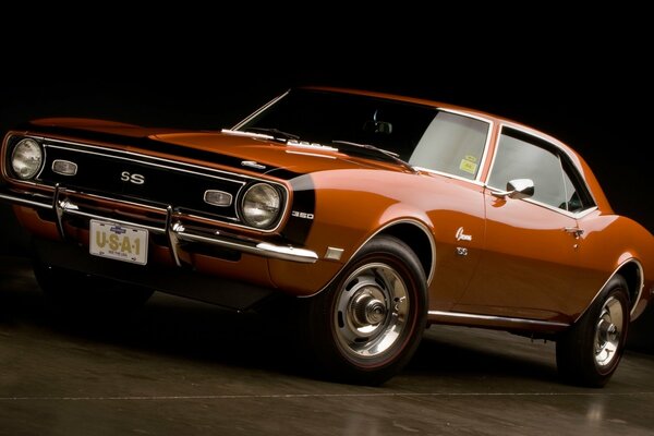 Orange 1968 chevrolet camaro on a dark background