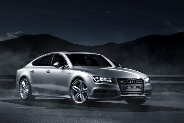 Audi a7 grau auf dunklem Hintergrund mit Bergen